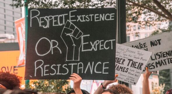 Close up of a protest sign that says "Respect existence of expect resistance"